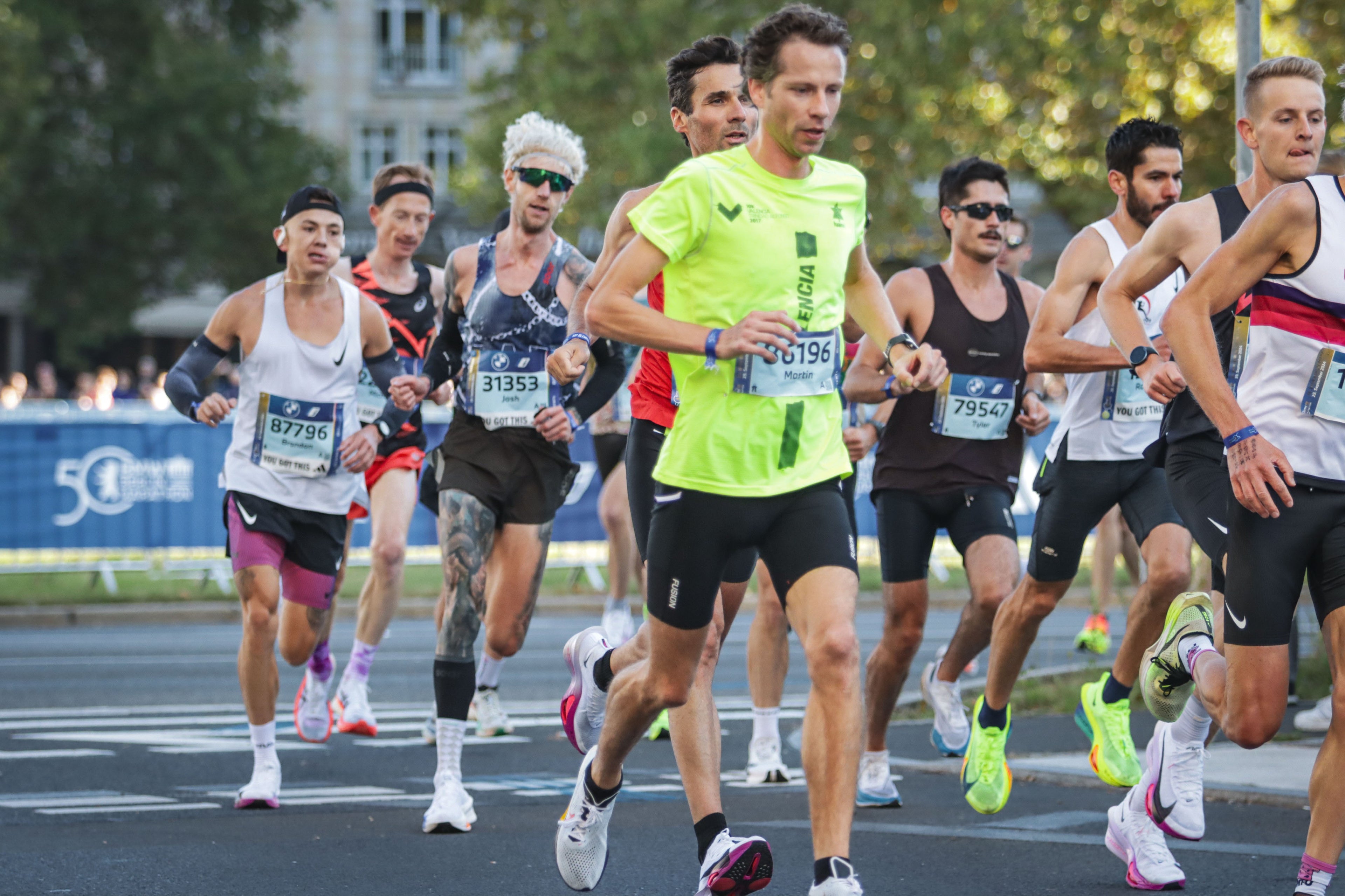 Runners participating in a marathon with visible race numbers on a street.