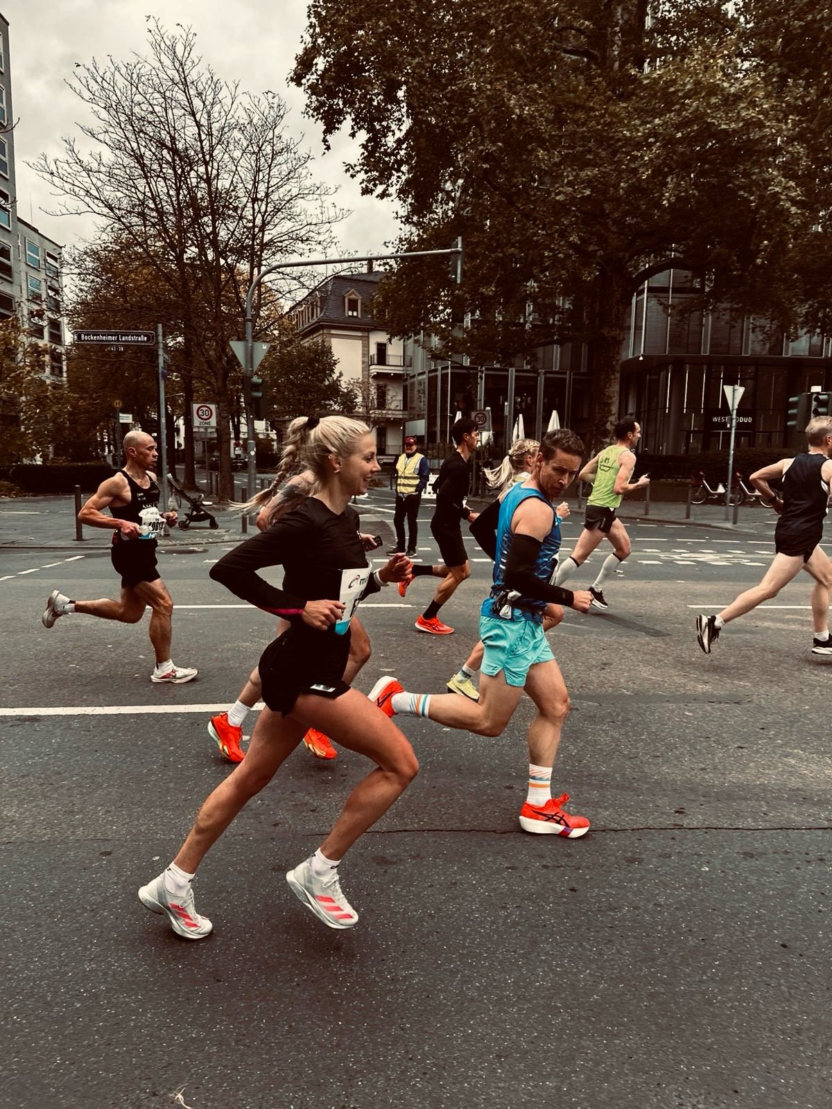 Runners in a street race with trees and buildings in the background